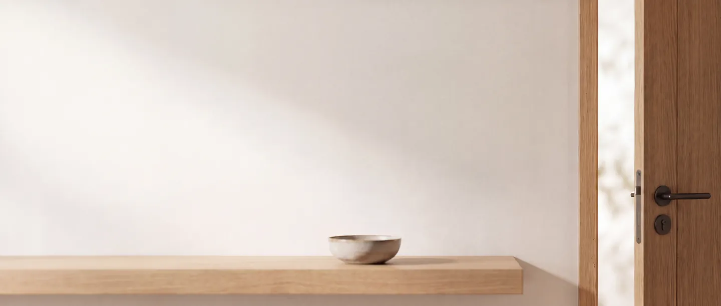 Centrale d'alarme Staniot H700 à écran tactile 7 pouces fixée au mur blanc d'une entrée, au-dessus d'une console en chêne, près d'une porte entrouverte