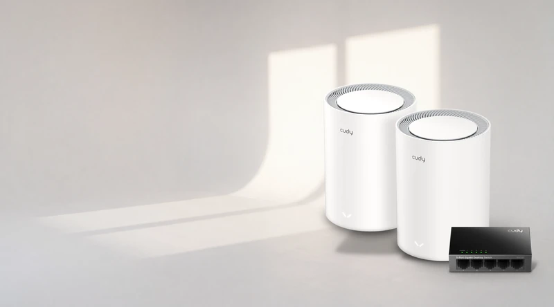Les deux bornes Wi-Fi 6 mesh Cudy M3000 et le switch Cudy GS105, posés au sol dans la lumière d'une fenêtre